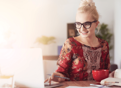 Frau mit markanter Brille sitzt im Homeoffice am Schreibtisch und blickt in einen Laptop - Die richtige Jobauswahl