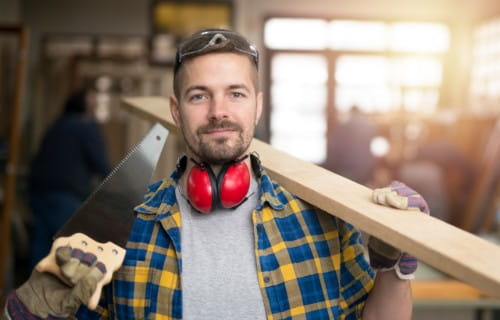Tischler mit Holzbrett und Werkzeug