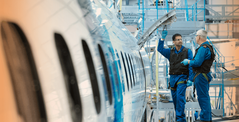 2 Ingenieure stehen auf einer Plattform neben einem Flugzeug in der Wartungshalle
