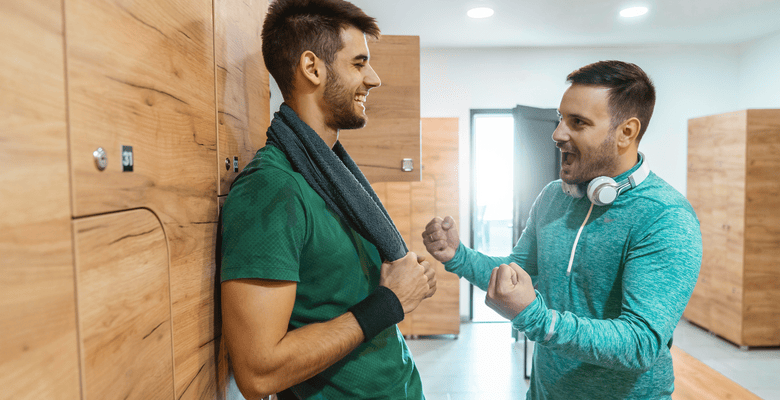 Zwei Männer in Sportbekleidung unterhalten sich im Umkleideraum.