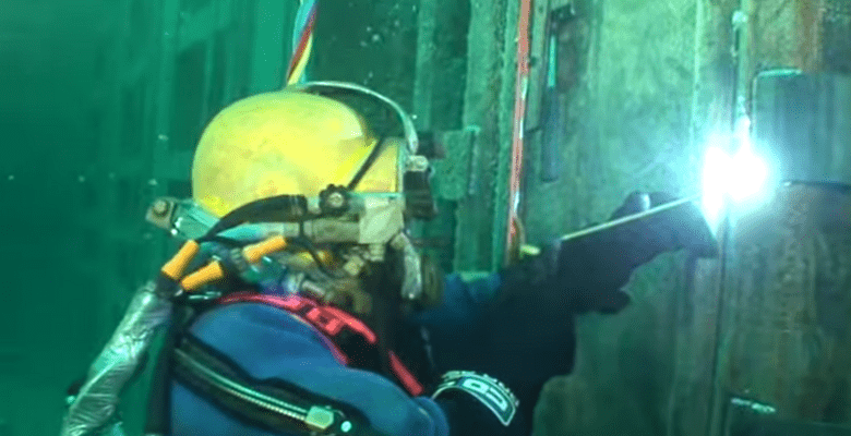 Ein Unterwasserschweißer in voller Ausrüstung mit seinem Werkzeug arbeitend