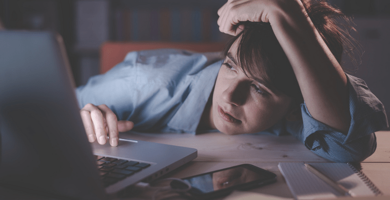Frau im Dunkeln völlig übermüded vor ihrem Laptop hängend