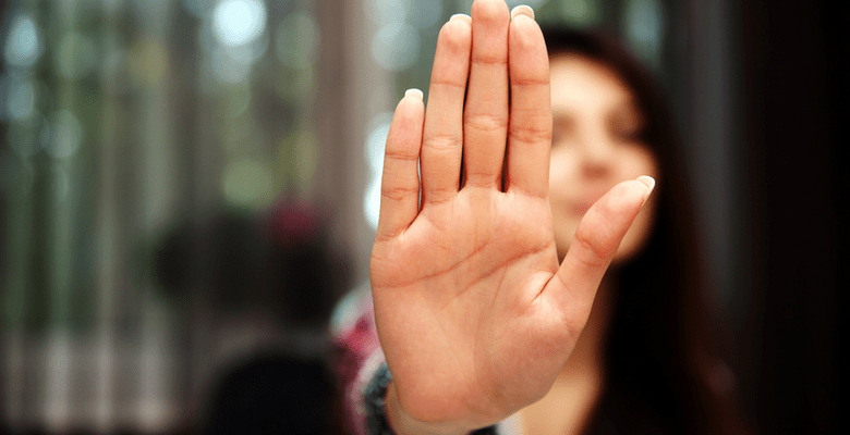 Person verschwommen im Hintergrund hält flache Hand nach vorne in die Kamera