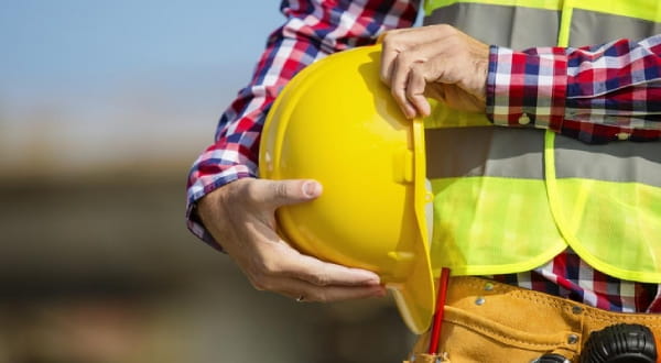 Bauarbeiterhelm wird im Arm gehalten