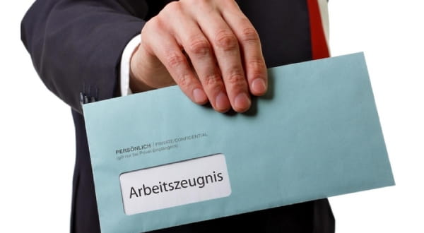 Anzugträger hält großen Blauen Brief mit "Arbeitszeugnis" in Hand