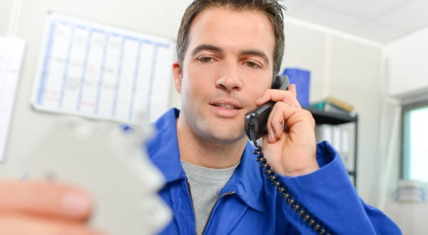 Mann telefoniert, betrachtet dabei ein Teil in seiner Hand