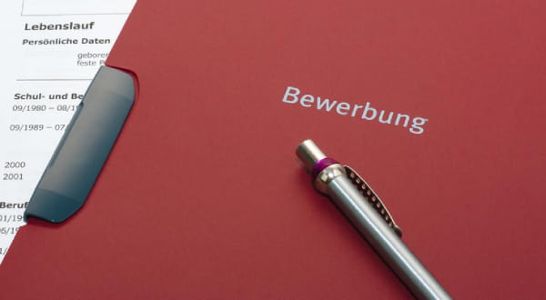 Klassische Bewerbungsmappe mit darauf liegendem Stift
