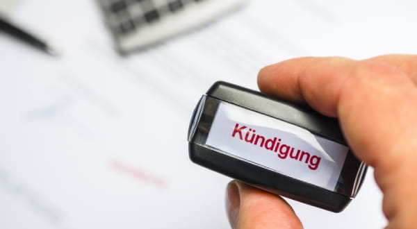 Hand hält kleines Schild mit "Kündigung" 