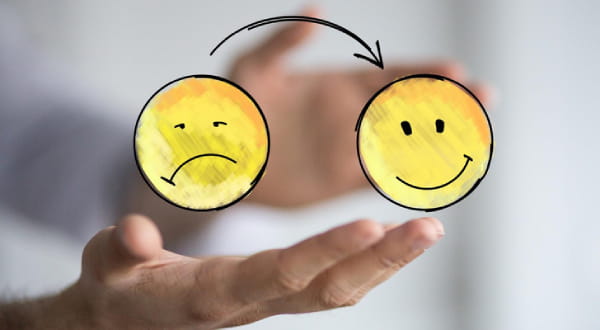 Pfeil zeigt vom schlecht gelaunten Smiley auf glücklichen Smiley
