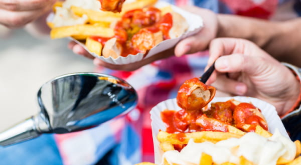 Nahaufnahme: Pommes und Currywurst wird gegessen