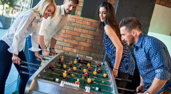 4 Personen am Tischkicker spielen