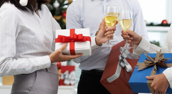 Personen halten Weihnachtsgeschenke und stoßen mit Getränken an