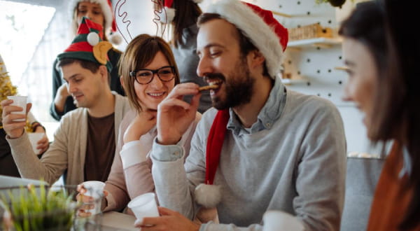 Gruppe mit Weihnachtsmützen, am lachen, essen, trinken